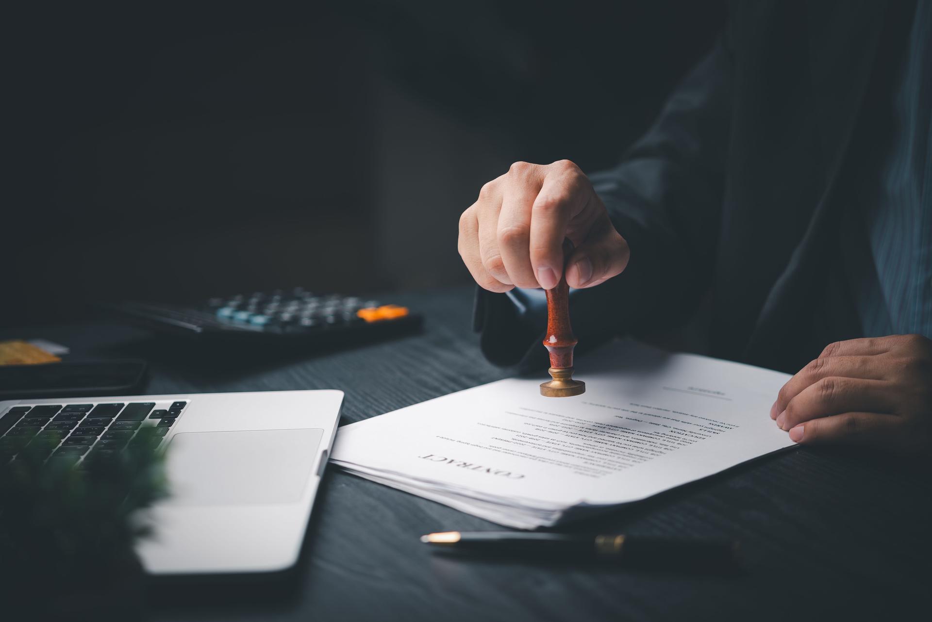 Man stamping approval of work finance banking or investment marketing documents on desk.